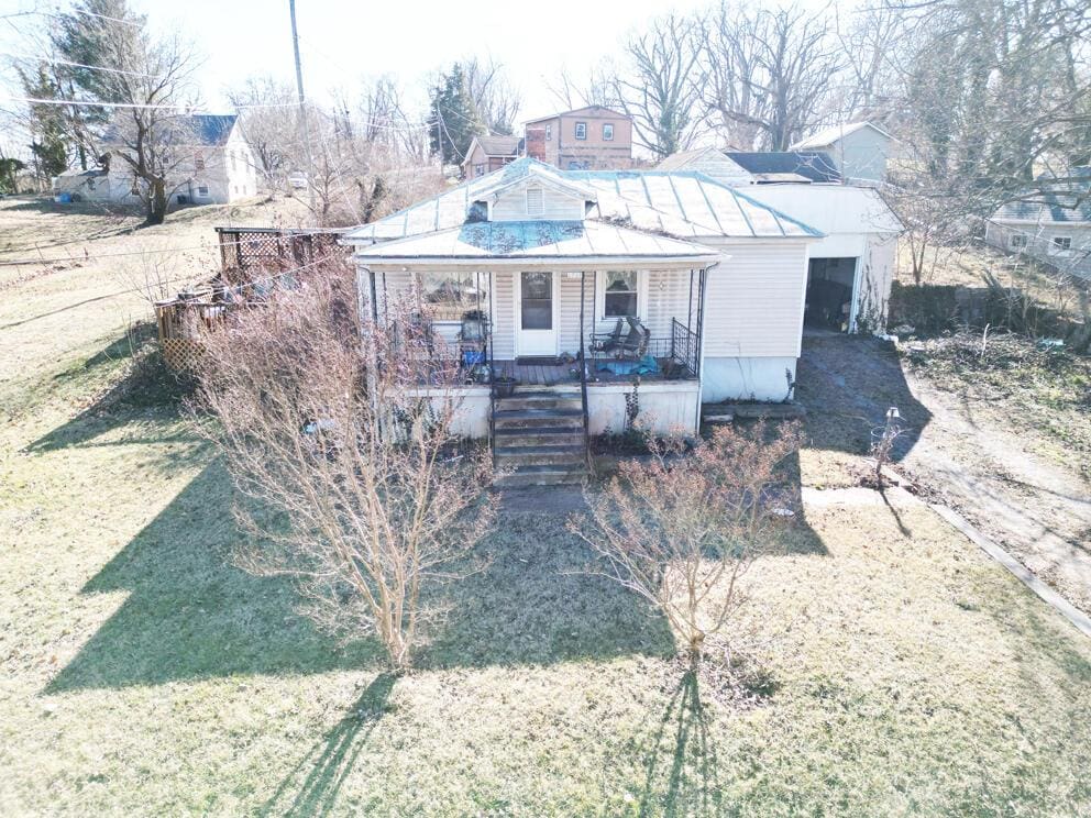 back of property featuring a lawn and covered porch