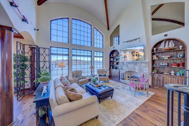 living room featuring ornate columns, light hardwood / wood-style flooring, a fireplace, and built in shelves