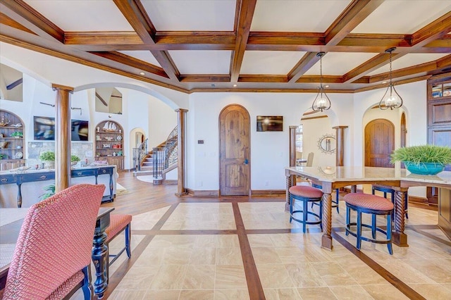 dining room with coffered ceiling, ornamental molding, built in shelves, beamed ceiling, and ornate columns