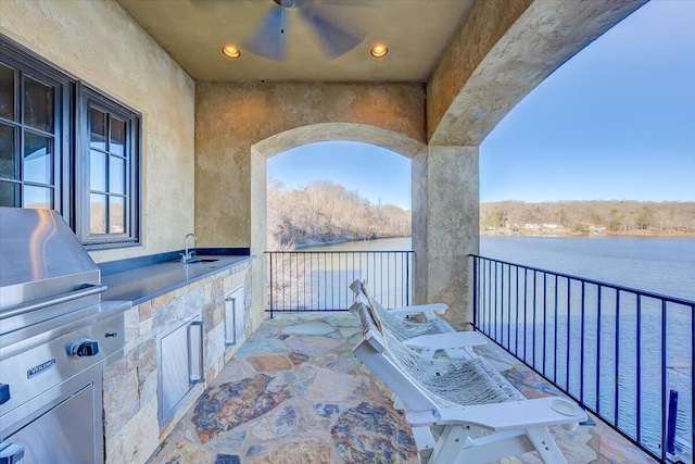 view of patio featuring a water view, area for grilling, ceiling fan, and sink