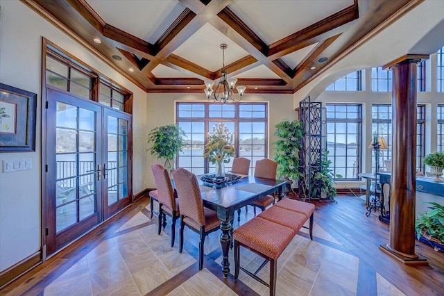 dining room featuring ornate columns, a towering ceiling, a chandelier, coffered ceiling, and french doors