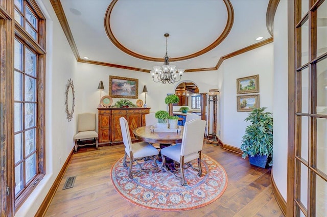 dining space featuring an inviting chandelier, hardwood / wood-style floors, and crown molding