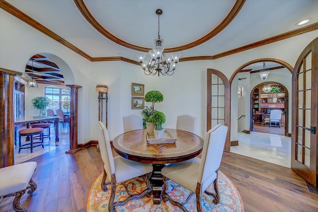 dining space with wood-type flooring, ornamental molding, a notable chandelier, and french doors