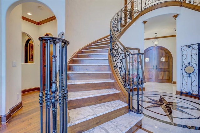 stairs featuring a high ceiling, crown molding, and hardwood / wood-style flooring