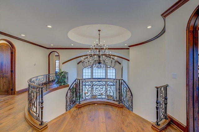 staircase featuring hardwood / wood-style flooring, ornamental molding, and an inviting chandelier