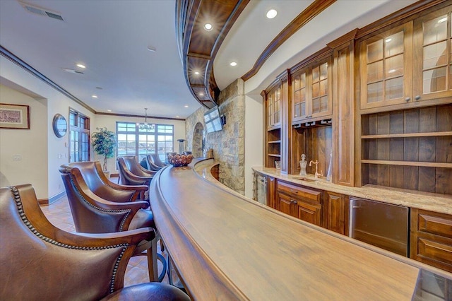 bar featuring crown molding, an inviting chandelier, light stone counters, and decorative light fixtures