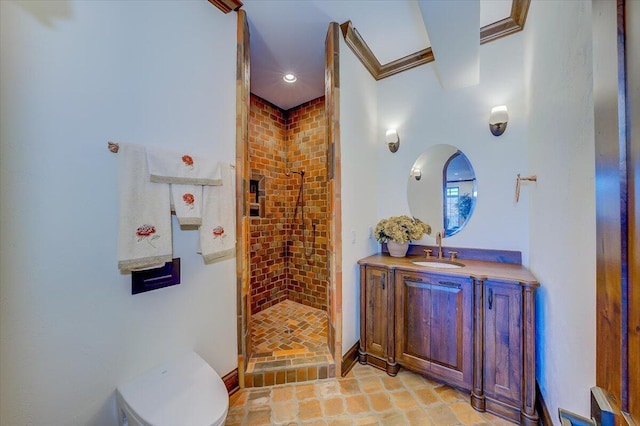 bathroom featuring ornamental molding, vanity, toilet, and a tile shower