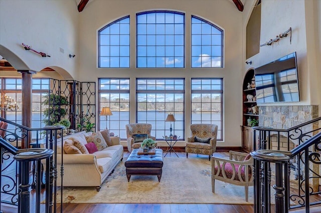 living room featuring a towering ceiling, decorative columns, and light wood-type flooring