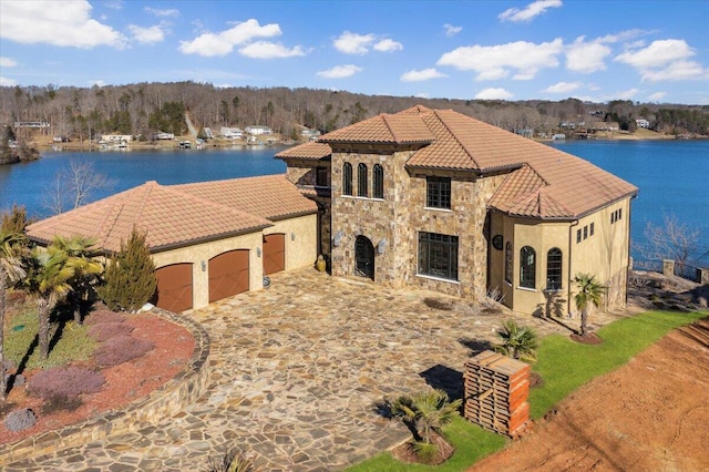 mediterranean / spanish home featuring a garage and a water view