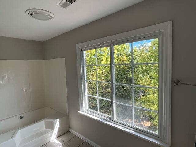 bathroom featuring washtub / shower combination, tile patterned floors, and a wealth of natural light