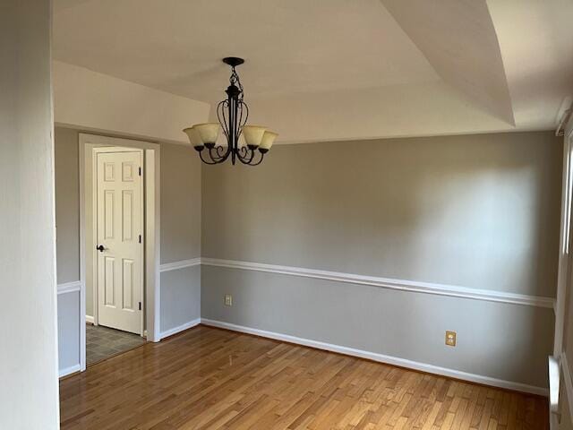 spare room with hardwood / wood-style floors and a chandelier