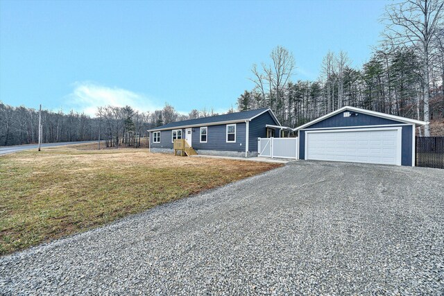 view of front of house featuring a front yard, fence, an outbuilding, and a detached garage