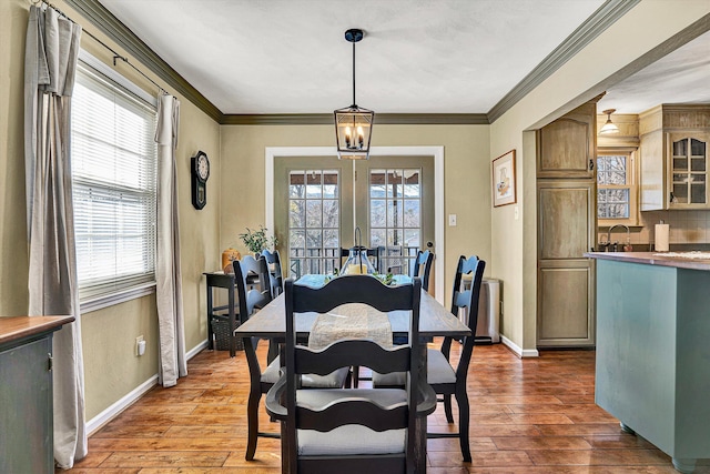 dining area featuring french doors, crown molding, and light hardwood / wood-style flooring