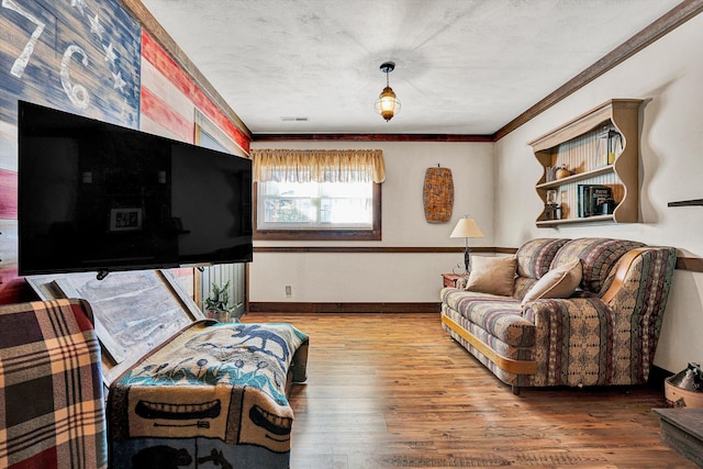 sitting room featuring hardwood / wood-style floors, ornamental molding, and a textured ceiling