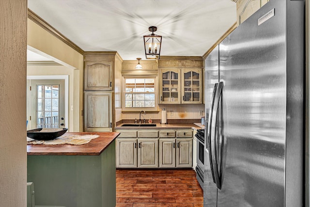 kitchen with appliances with stainless steel finishes, butcher block counters, sink, ornamental molding, and dark wood-type flooring