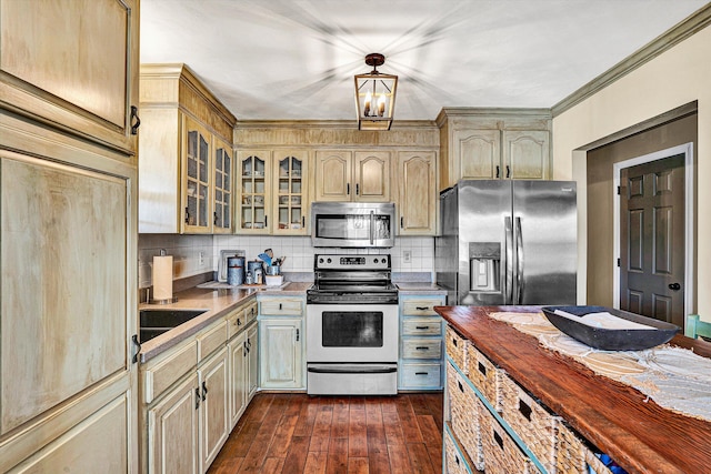 kitchen featuring tasteful backsplash, a chandelier, ornamental molding, appliances with stainless steel finishes, and dark hardwood / wood-style flooring