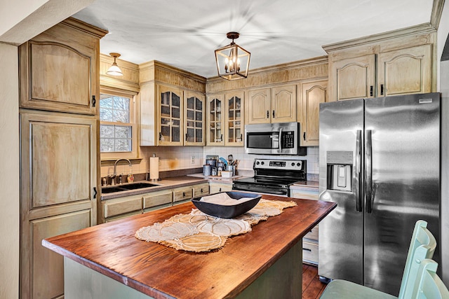 kitchen featuring sink, appliances with stainless steel finishes, hanging light fixtures, a center island, and decorative backsplash