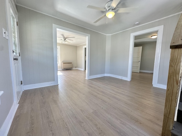 unfurnished room featuring baseboards, ornamental molding, heating unit, and light wood-style floors