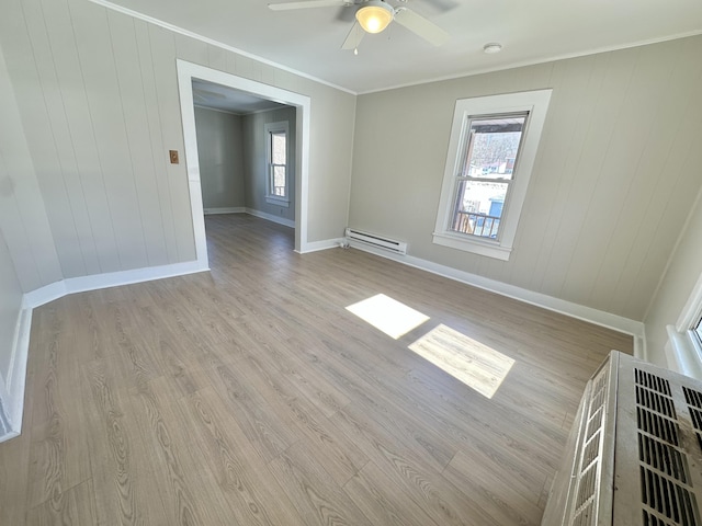 unfurnished room with ornamental molding, a wealth of natural light, light wood finished floors, and baseboard heating