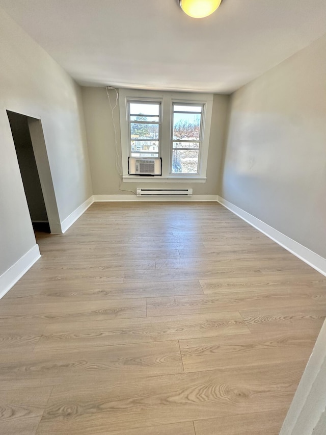 spare room with light wood finished floors, baseboards, and baseboard heating