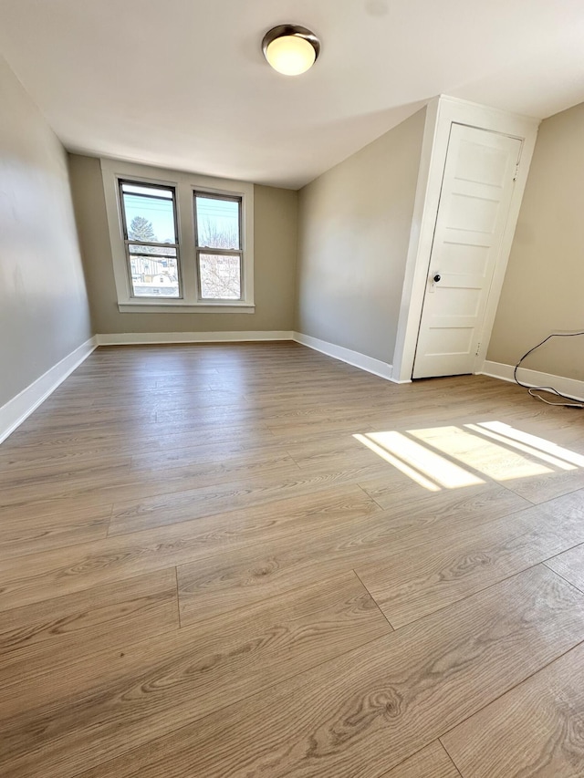 unfurnished room with light wood-type flooring and baseboards