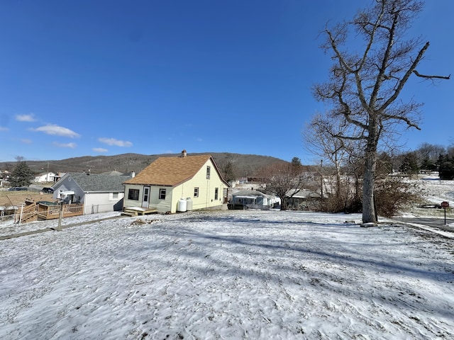 snow covered property featuring fence and a mountain view