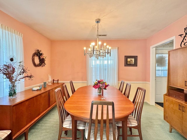 carpeted dining space with an inviting chandelier and a healthy amount of sunlight