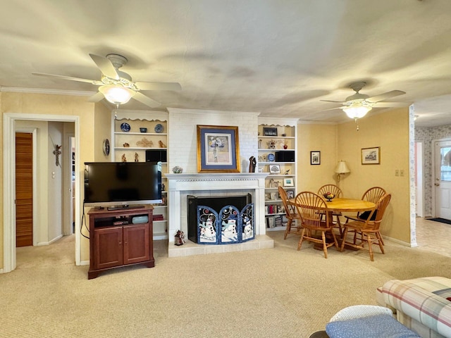 carpeted living room featuring crown molding, built in features, a large fireplace, and ceiling fan