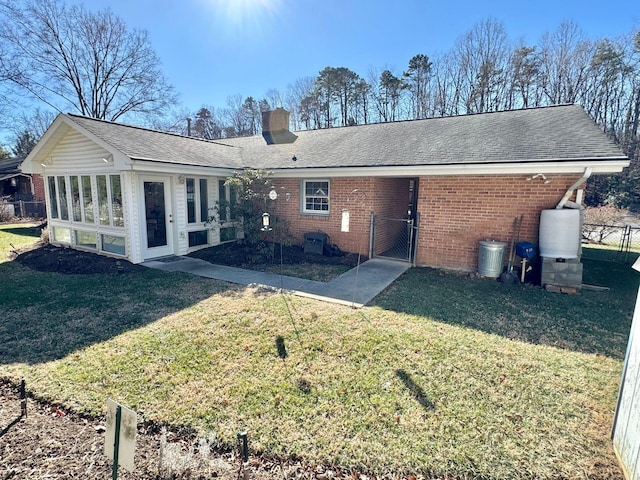 rear view of house with a sunroom and a lawn