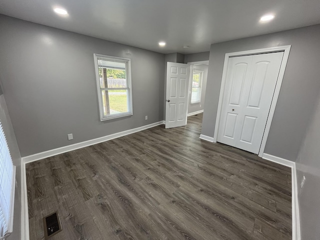 unfurnished bedroom featuring dark hardwood / wood-style flooring and a closet