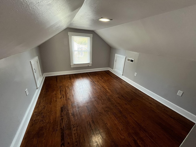 bonus room with dark hardwood / wood-style flooring, vaulted ceiling, and a textured ceiling