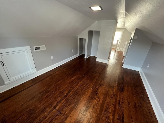 bonus room featuring lofted ceiling, dark wood-type flooring, and a textured ceiling