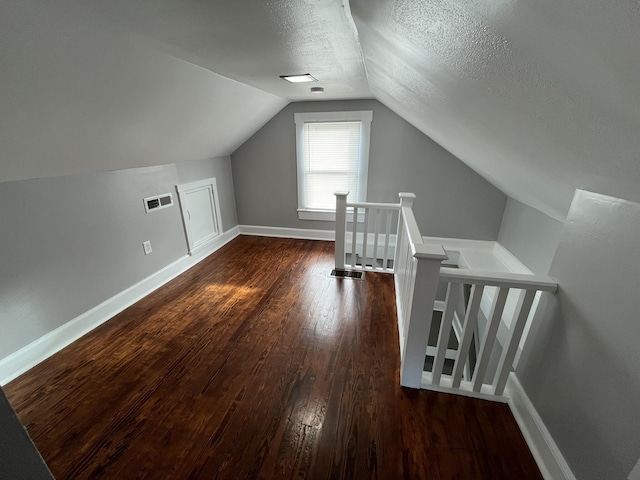 bonus room featuring vaulted ceiling, dark hardwood / wood-style floors, and a textured ceiling