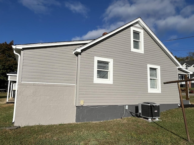 view of side of home with a yard and central AC