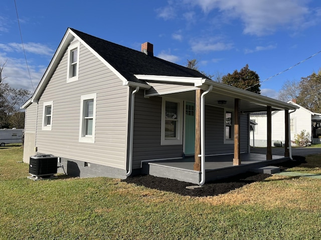 view of side of property featuring a yard, central AC, and covered porch