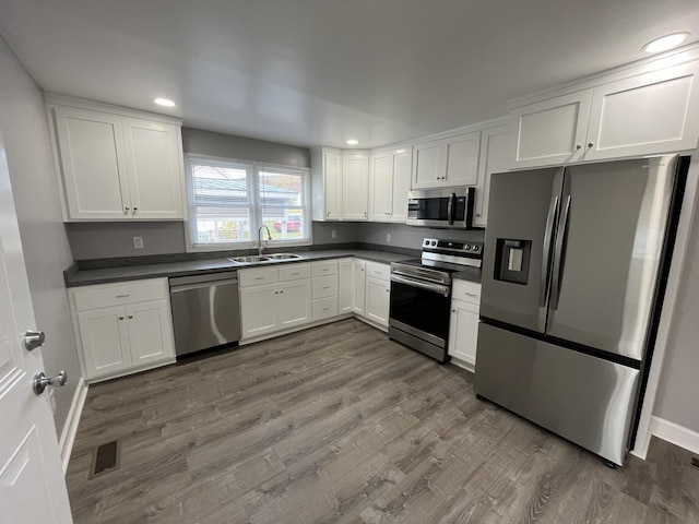 kitchen with dark wood-type flooring, appliances with stainless steel finishes, sink, and white cabinets