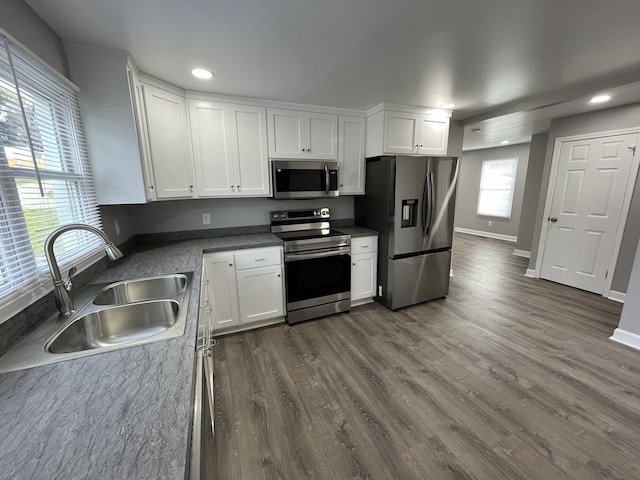 kitchen with appliances with stainless steel finishes, sink, white cabinets, and dark hardwood / wood-style flooring