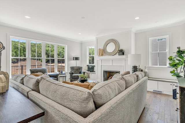 living room featuring visible vents, a brick fireplace, plenty of natural light, and crown molding