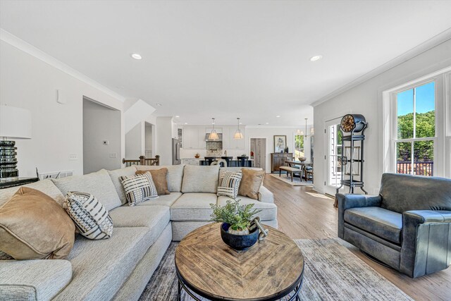 living area featuring recessed lighting, ornamental molding, and light wood finished floors