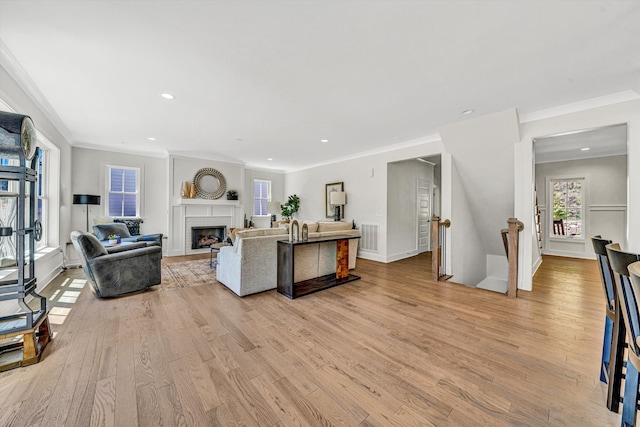 living area featuring recessed lighting, ornamental molding, light wood-style flooring, and a fireplace
