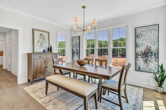 dining space featuring an inviting chandelier, baseboards, ornamental molding, and light wood finished floors