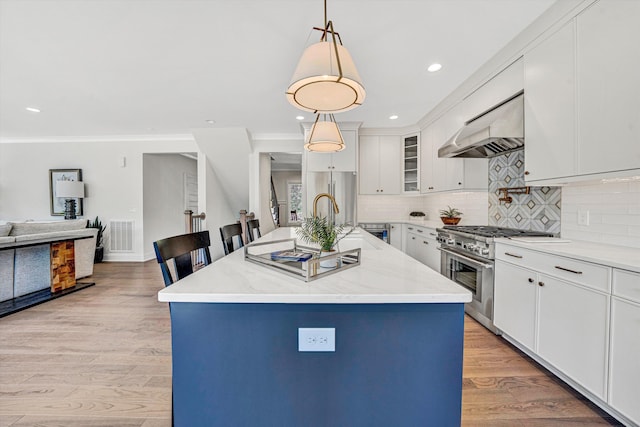 kitchen with stainless steel stove, white cabinetry, decorative light fixtures, range hood, and backsplash