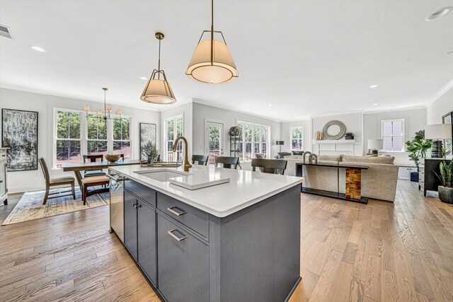 kitchen featuring ornamental molding, plenty of natural light, gray cabinets, a sink, and light wood-style flooring