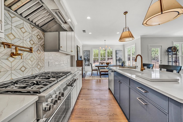 kitchen with a sink, light wood-style floors, stainless steel appliances, recessed lighting, and wall chimney exhaust hood