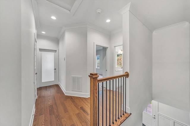 hall featuring baseboards, an upstairs landing, wood finished floors, visible vents, and ornamental molding