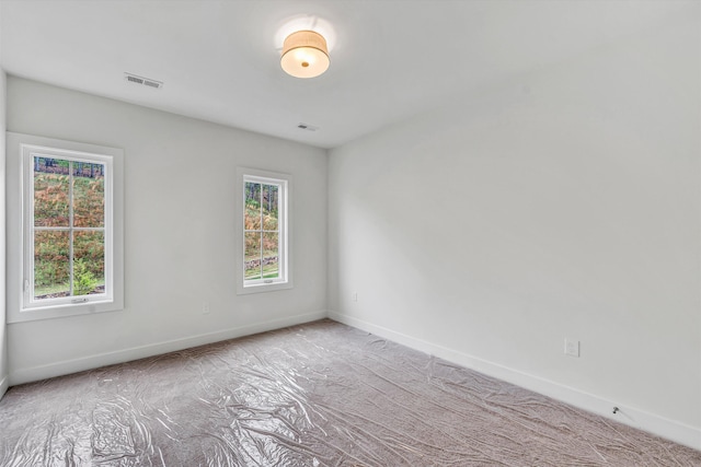 carpeted spare room featuring visible vents, baseboards, and a healthy amount of sunlight
