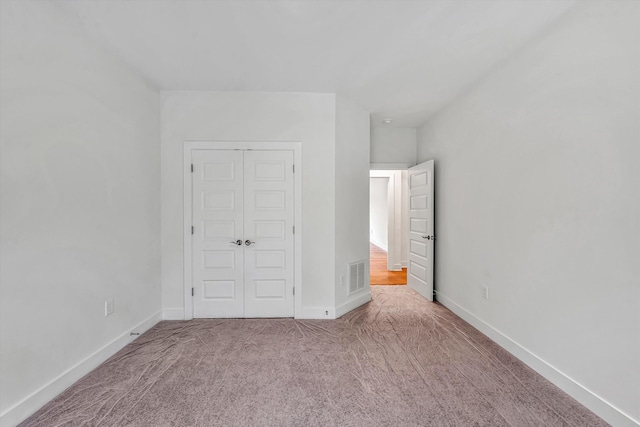 unfurnished bedroom featuring visible vents, baseboards, carpet floors, and a closet