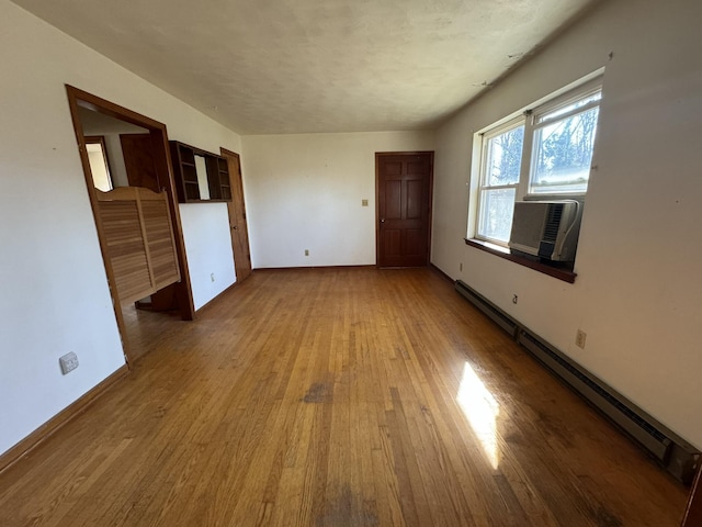 spare room featuring cooling unit, a baseboard radiator, wood-type flooring, and a textured ceiling