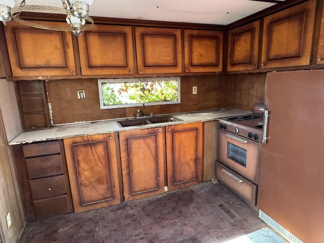 1075 Windstar Cir, Vinton, VA 24179 - kitchen featuring freestanding refrigerator, a sink, brown cabinetry, gas range oven, and light countertops