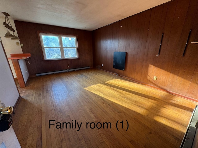 unfurnished living room featuring baseboard heating, wooden walls, and light hardwood / wood-style flooring